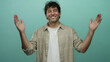 © Krakenimages.com - Hispanic man smiling and gesturing big size with hands against green background in an expressive pose showing joy and friendliness