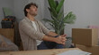 © Krakenimages.com - Handsome man sitting in new home surrounded by moving boxes and plants contemplating future decisions