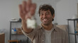 © Krakenimages.com - Smiling man holding house keychain, symbolizing new home ownership in a warm indoor setting.