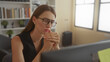 © Krakenimages.com - Young woman with clasped hands and glasses at computer in office building; concern decision making focus.