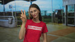 © Krakenimages.com - Woman showing peace sign with hand at airport terminal outdoors wearing red volunteer tshirt and smiling with closed eyes; optimism solidarity.