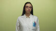 © Krakenimages.com - Hispanic female scientist in a white uniform with red glasses stands against a yellow wall, appearing thoughtful and contemplative.