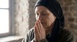 © AlfaSmart - Elderly woman praying with clasped hands and closed eyes. Concept of prayer, faith, spirituality and devotion to God for religious purpose.