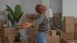 © Krakenimages.com - Young woman stretches arms and smiles broadly amid stacked cardboard boxes in a spacious building; optimism.