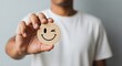 © Visi Hue - Man holding smiley face emoticon with wink expression showing positive emotion and happiness mood