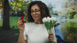 © Krakenimages.com - Middle-aged hispanic woman in park holding engagement ring and white tulips, signaling romantic proposal in vibrant outdoor setting.