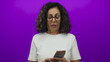 © Krakenimages.com - Middle-aged hispanic woman examining mexican pesos against an isolated purple background, highlighting the concept of finance and economics.