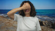 © Krakenimages.com - Middle-aged hispanic woman stands smiling at seaside beach with blue ocean backdrop on a sunny day.