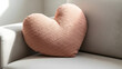 © IftiarJony - A pink heart-shaped pillow sitting on a white couch in a bright room