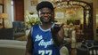 © Krakenimages.com - Man holds out hand toward camera in hotel building interior wearing blue basketball jersey and smiling; hospitality friendly.