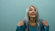 © Krakenimages.com - Senior woman with grey hair pointing at herself against an isolated blue background wall displaying confident expression.