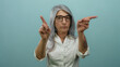 © Krakenimages.com - Senior woman with grey hair gesturing no with her fingers against a blue background, asserting a strong negative expression in an isolated, focused setting.