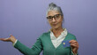 © Krakenimages.com - Senior woman with grey hair holding a credit card and gesturing something on an isolated purple background depicts finance concept