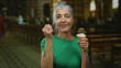 © Krakenimages.com - Senior woman with grey hair in a church enjoying ice cream, capturing a joyful and serene moment inside a sacred space with a vibrant and lively expression.