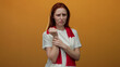 © Krakenimages.com - Woman with red hair in a white shirt holds her wrist in pain against an orange background, expressing discomfort and emotion while wearing a scarf.