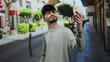 © Krakenimages.com - Young man taking selfie on urban street with smartphone features outdoor setting, casual attire, and vibrant cityscape background