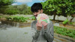 © Krakenimages.com - Man holding norwegian banknotes outdoors in a vibrant park setting, smiling confidently surrounded by lush greenery, showcasing currency in a bright natural environment.