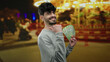 © Krakenimages.com - Man smiling holding russian ruble banknotes at an outdoor fair with vibrant lights and blurred background, implying excitement and success
