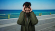 © Krakenimages.com - Handsome man standing on a seaside promenade with a jacket, expressing various emotions against the blue sea and sky backdrop, capturing a young adult enjoying the serene beachscape.