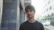 © Krakenimages.com - Man gazes with steady stare and visible face beside city street building facade; introspection serenity.