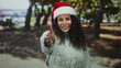 © Krakenimages.com - Woman smiling in park wearing santa hat and sweater reaching out hand during christmas holiday outdoors.