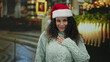© Krakenimages.com - Woman wearing santa hat standing in a festive church with glowing candles and holiday decor, expressing emotion and warmth in an indoor christmas setting.