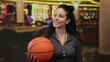 © Krakenimages.com - Woman smiling in casino interior holding basketball next to slot machines showcasing a vibrant indoor scene.