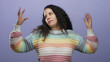 © Krakenimages.com - Woman gesturing with hands in colorful sweater against isolated purple wall, exuding expressive and thoughtful vibe distinctively capturing hispanic identity and emotion.