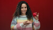 © Krakenimages.com - Woman holding red heart and showing thumbs up on an isolated red background, expressing positivity and love in a cheerful, colorful setting, perfect for valentine promotions.
