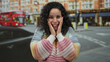 © Krakenimages.com - Woman expressing joy with hands on cheeks wearing colorful sweater on an urban street with iconic red double-decker bus in background.