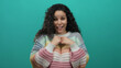 © Krakenimages.com - Woman expressing emotion wearing colorful sweater against isolated green background showing excitement and surprise with curly hair and cheerful smile.