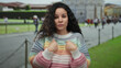 © Krakenimages.com - Young hispanic woman in colorful sweater expresses surprise while pointing at herself against the backdrop of pisa tower, outdoor tourist setting with blurred crowd in italy.