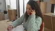 © Krakenimages.com - Young woman talking on phone and writing in notebook surrounded by moving boxes in a new home apartment living room interior.