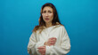 © Krakenimages.com - Young woman standing isolated against a vibrant blue background wearing a white sweater, showcasing a thoughtful expression and natural hair flowing freely.