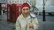 © Krakenimages.com - Woman holding tennis racket smiling in city street with iconic red phone booths, blending casual fashion with urban sports vibe, suggesting a vibrant and active lifestyle.