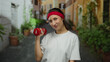 © Krakenimages.com - Woman exercising with dumbbell on a charming city street, wearing a red headband, and smiling casually in an outdoor urban setting.