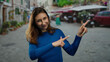 © Krakenimages.com - Woman smiling in blue sweater pointing on a bustling city street with blurred background, capturing urban exploration vibes and joyful moments outdoors.
