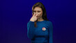 © Krakenimages.com - Young woman making a vigilance gesture in a blue sweater with a vote badge against a solid blue background, emphasizing the importance of voting participation and awareness.