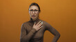 © Krakenimages.com - Woman showing shocked expression on orange background with glasses, wearing brown shirt, exhibiting surprise and emotion, isolated for expressive communication and illustrative content.