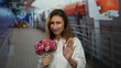 © Krakenimages.com - Woman holding flowers gestures no with fingers on a boat port, expressing a playful refusal during a lively outdoor scene in a maritime setting.
