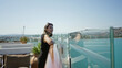 © Krakenimages.com - Woman leaning on glass rail with bare forearm resting on cruise ship deck railing, smiling toward sea and distant shore; serenity travel.