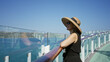 © Krakenimages.com - Woman smiles and leans on railing on building deck while wearing sunhat and sunglasses; serenity vacation.