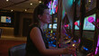 © Krakenimages.com - Woman holding a champagne glass drinking while playing slot machine in a casino building with neon lights; win joy.