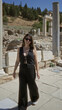 © Krakenimages.com - Woman walking and smiling while adjusting sunglasses at ancient stone building ruins in ephesus turkey; travel joy.