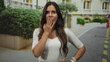 © Krakenimages.com - Woman with hand covering mouth on street in front of building, other hand on hip looking upward; surprise.