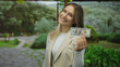 © Krakenimages.com - Young woman in a park smiling while holding a us dollar note showcasing happiness and wealth in an outdoor setting