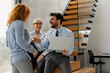 © Novak - Group of happy coworkers sharing a laugh while a man holds a laptop during a meeting