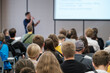 © Anton Gvozdikov - Live presentation in front of attentive audience in conference setting. Speaker explains slides and engages crowd through talk visuals in classroom style venue.