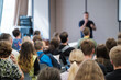 © Anton Gvozdikov - Presenter at front of room engaging crowd during seminar audience listening closely conference setting