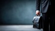 © Digital Design - A businessman in a suit holds a leather briefcase, exuding professionalism and readiness in a dimly lit environment.